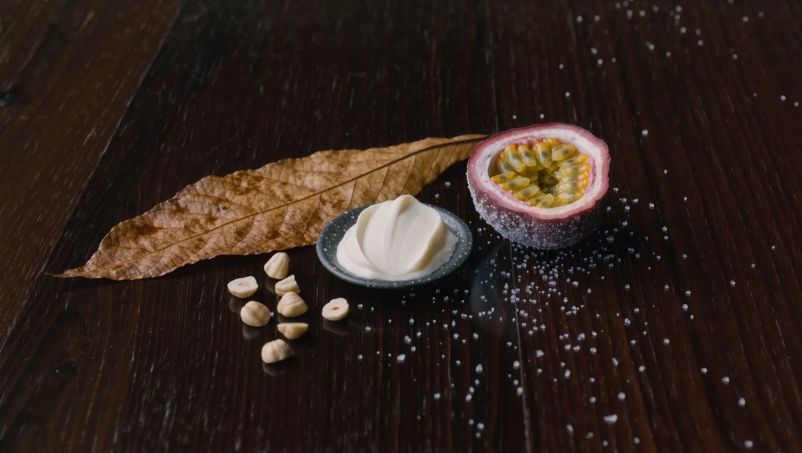 Illustration of a cured tobacco leaf, hazelnuts, cream and a frosted halved passion fruit on walnut, evoking TEREA Oasis Pearl