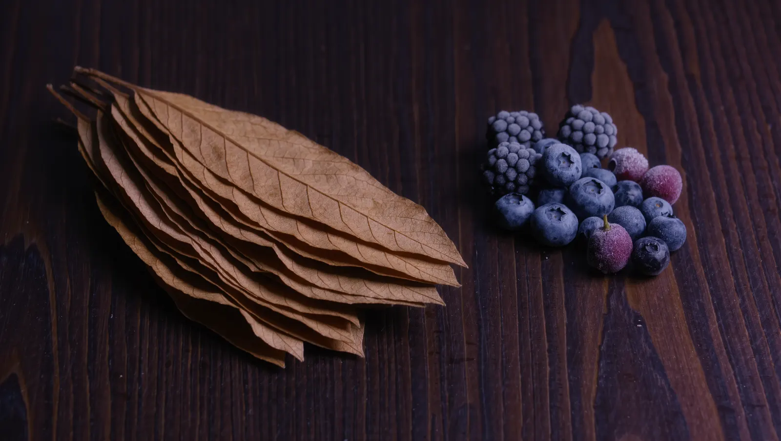 Illustration of cured tobacco leaves and frosted forest berries on walnut, evoking TEREA Purple Wave