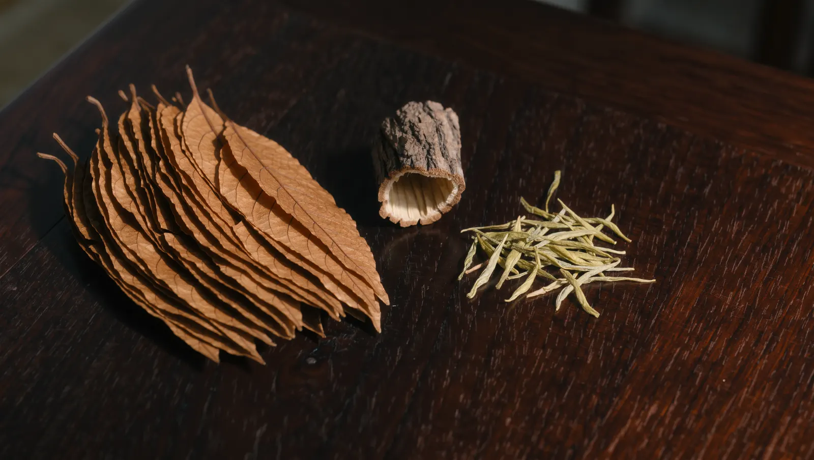 Illustration of tobacco leaves, loose tea leaves and cedar bark on a walnut table, evoking TEREA Sienna's flavor notes