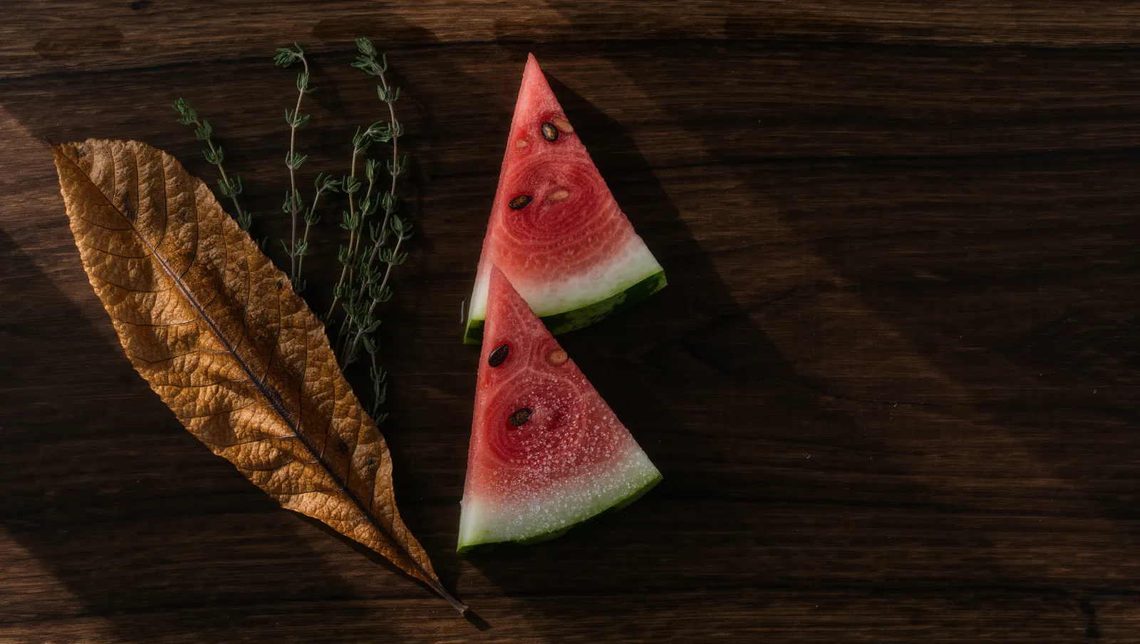 Illustration of a toasted tobacco leaf, dried herbs and frosted watermelon slices on walnut, evoking TEREA Sun Pearl