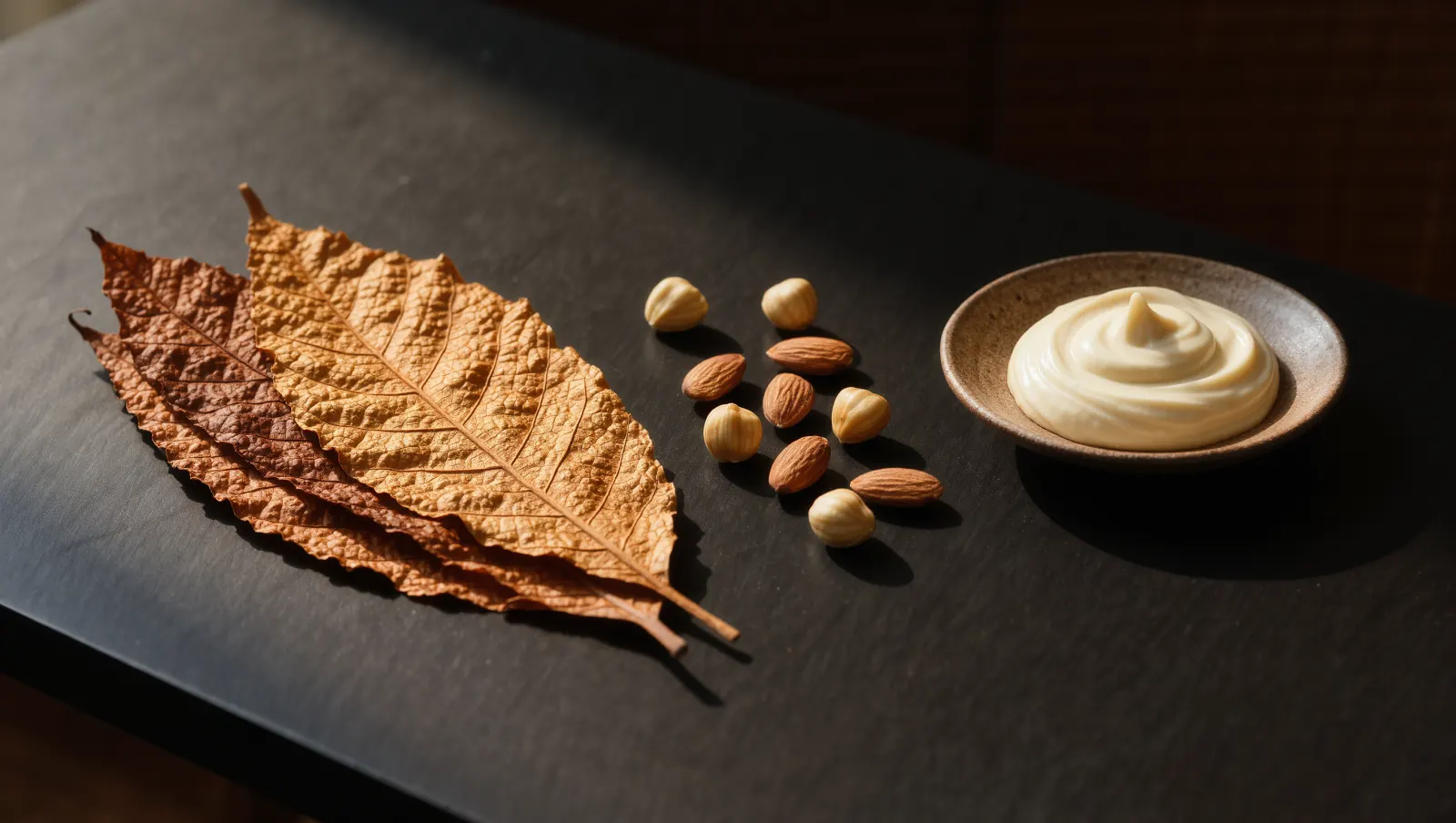 Illustration of toasted tobacco leaves, mixed roasted nuts and a dish of cream on a dark table, evoking TEREA Teak
